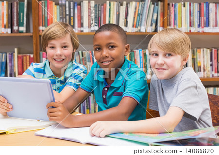 Cute pupils using tablet computer in library 14086820