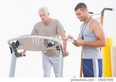 Senior man on treadmill with trainer 14087499