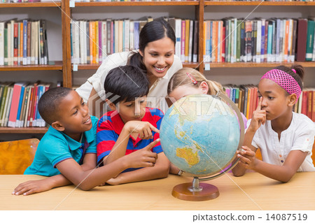 Cute pupils and teacher looking at globe in library Cute pupils and teacher looking at globe in library 14087519