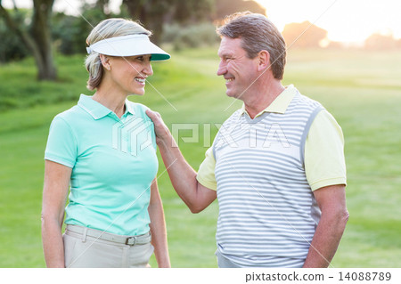 Golfing couple smiling at camera on the putting green Golfing couple smiling at camera on the putting green 14088789
