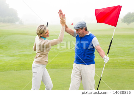 Stock Photo: Golfing couple high fiving on the golf course