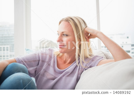 Thoughtful woman sitting on sofa Thoughtful woman sitting on sofa 14089192