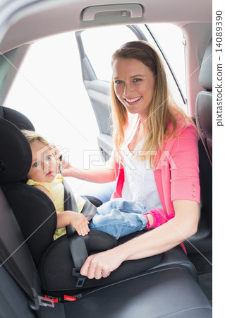 Mother securing her baby in the car seat Mother securing her baby in the car seat 14089390
