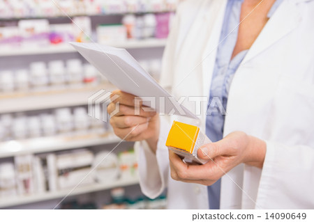 Pharmacist looking at prescription and medicine 14090649