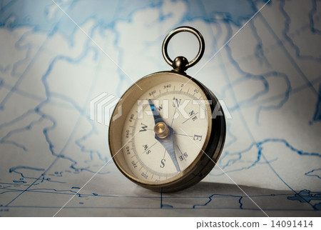 Magnetic compass standing upright on a map 14091414