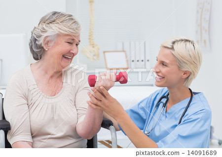 Nurse assisting senior patient in lifting dumbbell 14091689