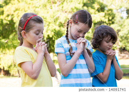 Children saying their prayers in park 14091741