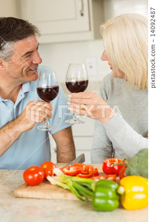 Happy mature couple having red wine while making dinner 14092487