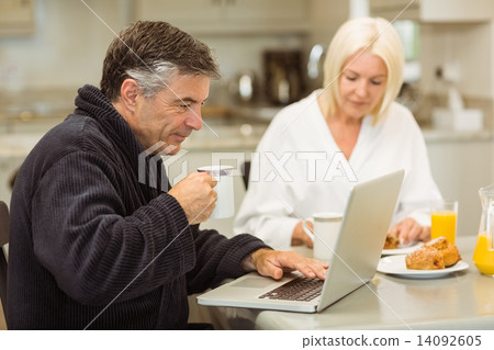 Mature couple having breakfast together man using laptop 14092605