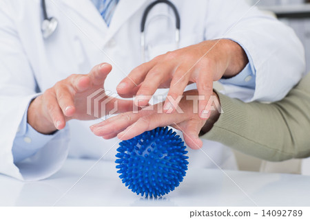 Doctor assisting female patient to hold massage ball 14092789