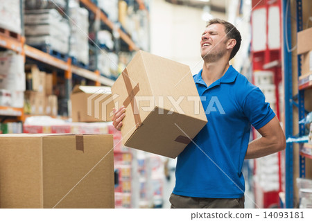 Worker with backache while lifting box in warehouse 14093181