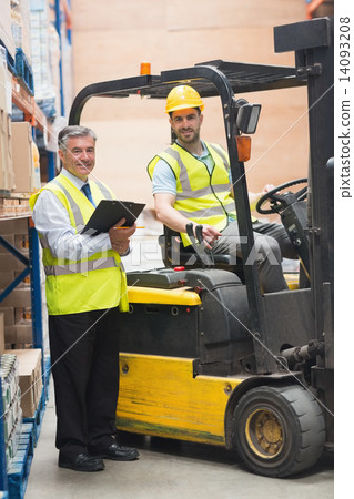 Driver operating forklift machine next to his manager Driver operating forklift machine next to his manager 14093208
