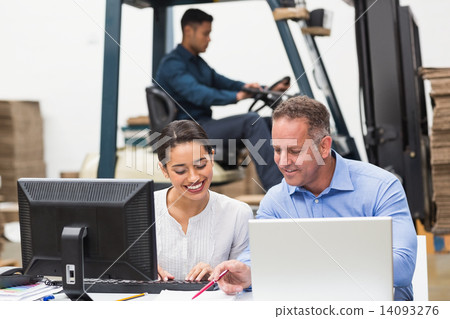 Warehouse managers working with laptop at desk 14093276