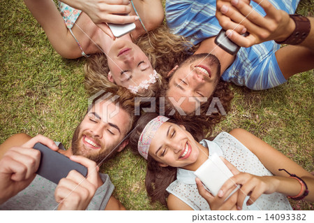 Hipsters lying on grass using smartphones 14093382