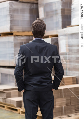 Warehouse manager in suit standing with hands in pockets 14093767