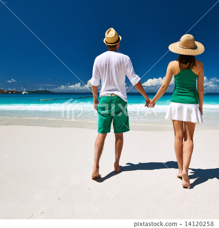 Couple in green walking on a beach at Seychelles 14120258