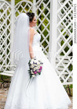 Young bride in a garden in a white dress with a bouquet Young bride in a garden in a white dress with a bouquet 14130421