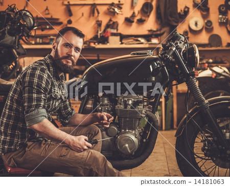 Mechanic building vintage style cafe-racer motorcycle  in custom garage 14181063