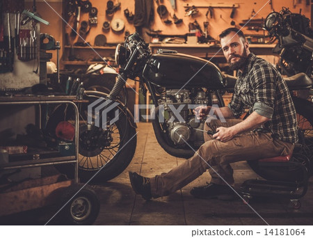Mechanic building vintage style cafe-racer motorcycle  in custom garage 14181064