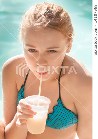 Little blond girl drinks cocktail in swimming pool Little blond girl drinks cocktail in swimming pool 14187968