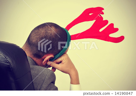 man with a reindeer antlers headband in his office chair, with a man with a reindeer antlers headband in his office chair, with a 14190847