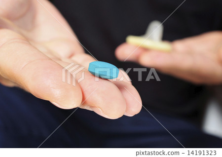 yougn man with blue pill and condom 14191323