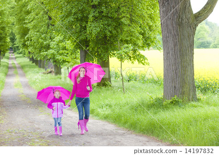 mother and her daughter with umbrellas in spring alley 14197832