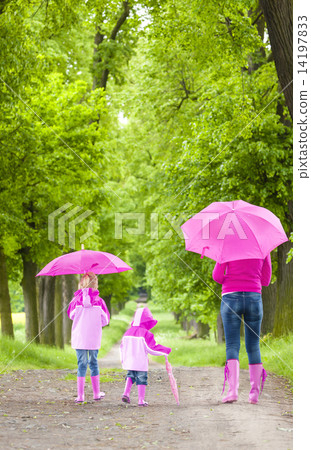 mother and her daughters with umbrellas in spring alley mother and her daughters with umbrellas in spring alley 14197833