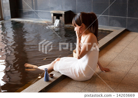 A young woman entering a hot spring and enjoying sake 14203669