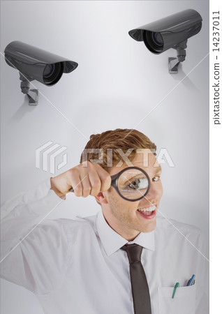 Composite image of geeky businessman looking through magnifying 14237011