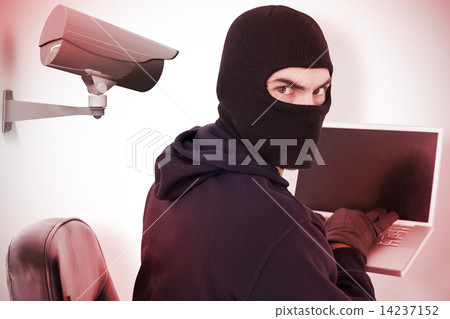 Composite image of hacker sitting and hacking laptop 14237152
