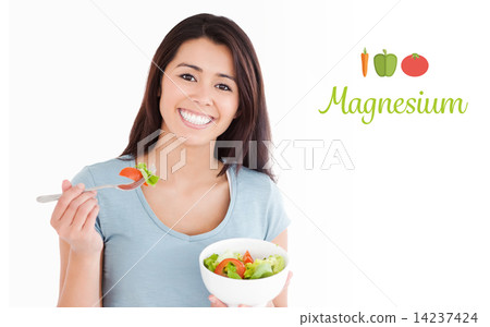 Magnesium against beautiful woman eating a bowl of salad 14237424