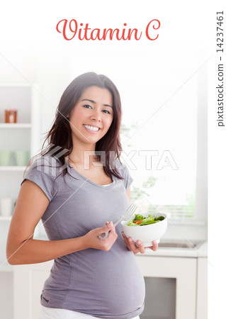 Vitamin c against gorgeous pregnant woman holding a bowl of sala Vitamin c against gorgeous pregnant woman holding a bowl of sala 14237461