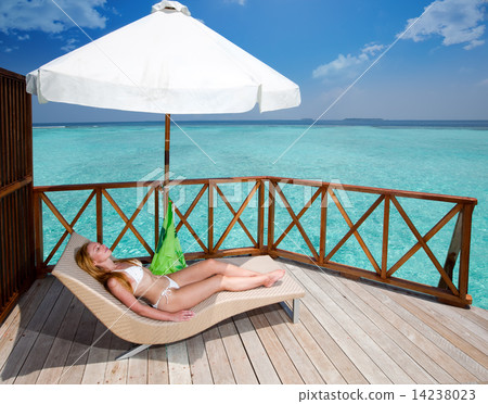 Young woman tans on a water villa terrace , Maldives Young woman tans on a water villa terrace , Maldives 14238023