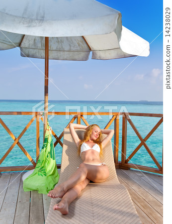 Young woman tans on a water villa terrace , Maldives 14238029