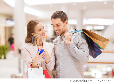 couple with smartphone and shopping bags in mall 14238432