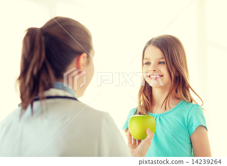 female doctor giving apple to smiling little girl 14239264