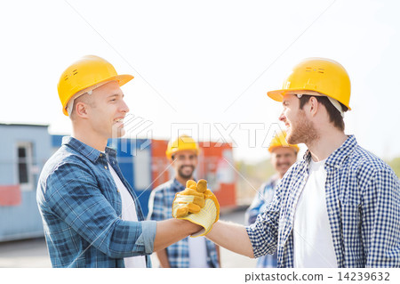 group of smiling builders in hardhats outdoors group of smiling builders in hardhats outdoors 14239632