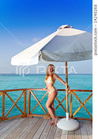 Young woman tans on a water villa terrace , Maldives.. Young woman tans on a water villa terrace , Maldives.. 14240268