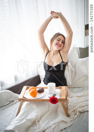 smiling woman having breakfast in bed and stretching hands smiling woman having breakfast in bed and stretching hands 14275389