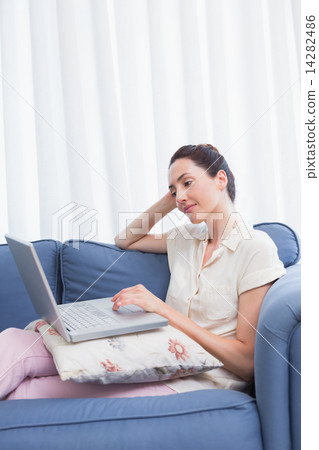 Casual brunette using laptop on couch Casual brunette using laptop on couch 14282486