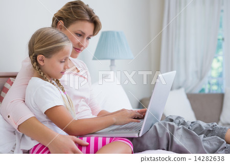 Mother and daughter using laptop in bed Mother and daughter using laptop in bed 14282638