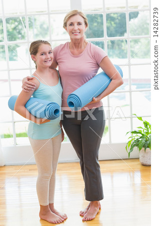 Mother and daughter holding yoga mats 14282739