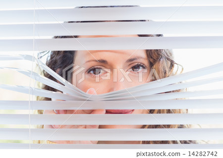 Curious woman looking through blinds 14282742