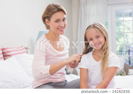 Mother brushing her daughters hair 14282830