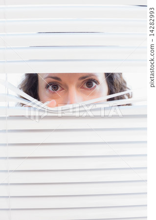 Curious woman looking through blinds Curious woman looking through blinds 14282993