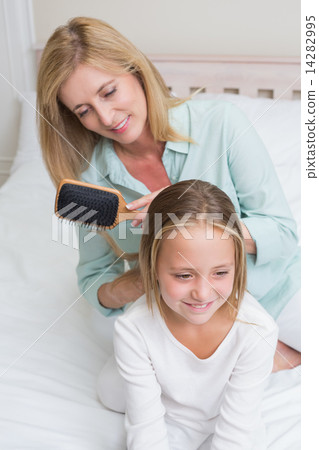Smiling mother brushing her daughters hair Smiling mother brushing her daughters hair 14282995