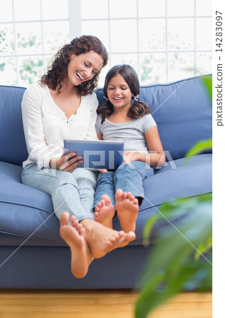Happy mother and daughter sitting on the couch and using tablet 14283097