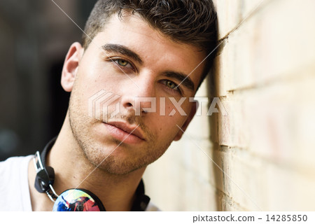 Young man in urban background listening to music with headphones Young man in urban background listening to music with headphones 14285850