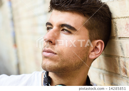 Handsome young man with blue eyes posing near a wall Handsome young man with blue eyes posing near a wall 14285851